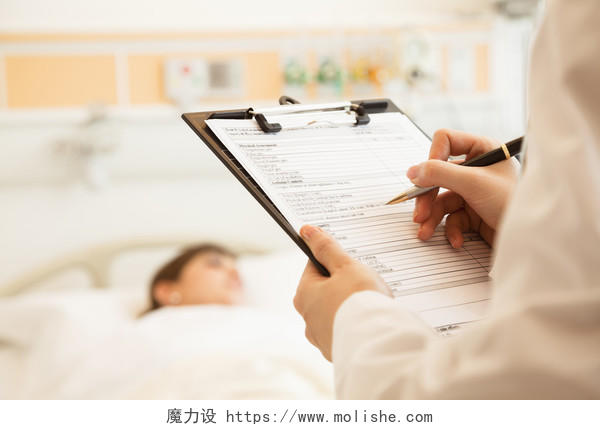 医生书写病历与患者躺在医院的病床上在背景上的特写